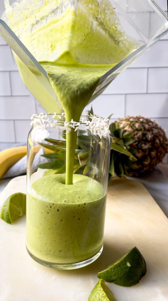 Tropical Green Smoothie! - An Actually Tasty Green Smoothie in a clear glass with coconut shreds on the rim. #cleaneating #greensmoothie #plantbased #breakfast #smoothie #mealplanning