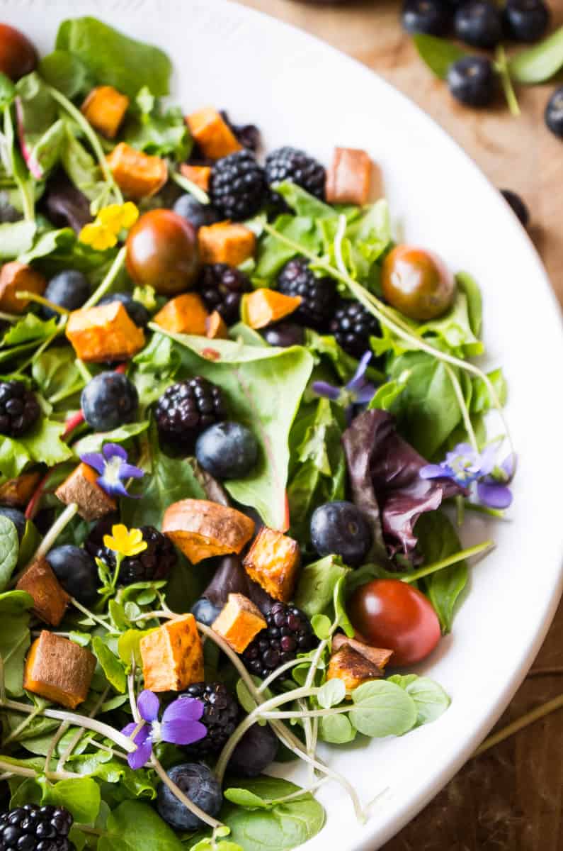 Veil of the Fairies Salad- A Whole30 vegetarian salad recipethat bursting with ripe Spring berries, dandelion greens, and topped with a delicious blueberry lemon basil beet dressing. 