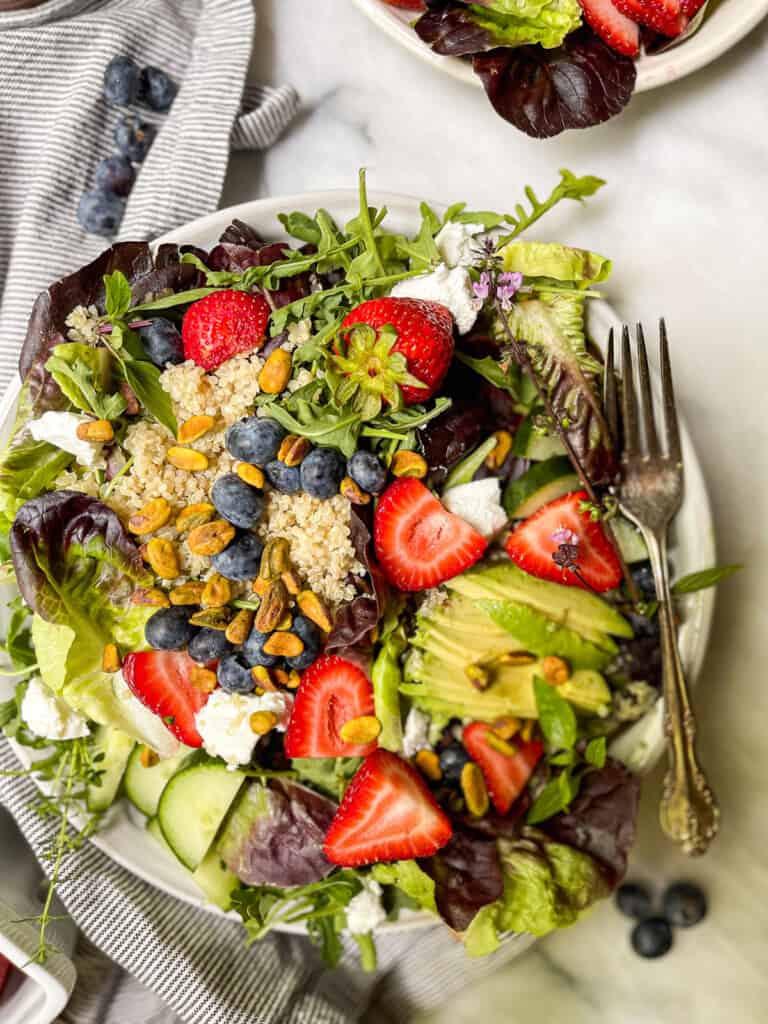 Mixed green salad with strawberries on a big plate 