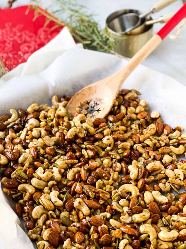 Roasted Rosemary Party Nuts on a Baking Sheet with wooden spoon for serving 