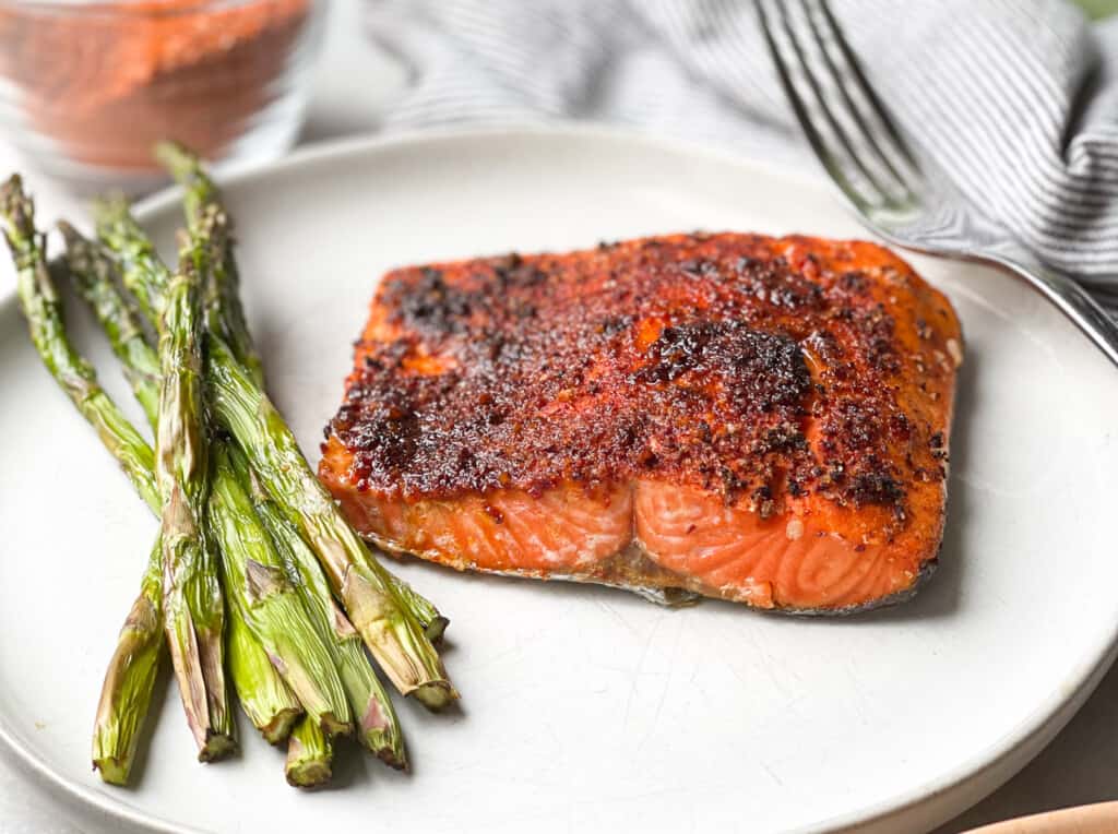 Chili Lime Air Fryer Salmon on a plate with a side of asparagus on a white marble table top.