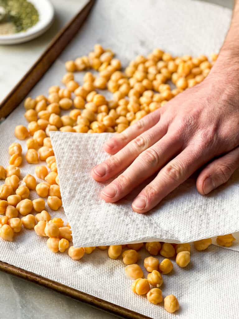 Tray of chickpeas being dried with paper towels as a process shot for Air Fryer Chickpeas 