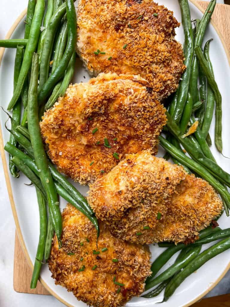 White platter with gluten free breaded air fryer pork chops and green beans
