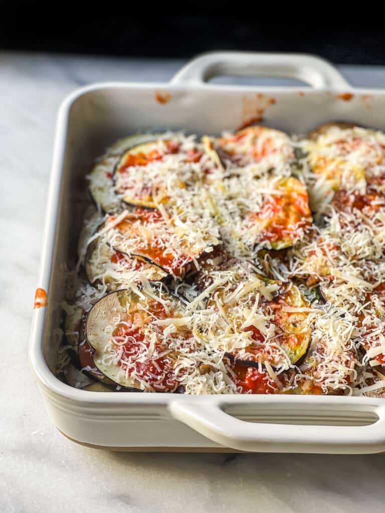 Uncooked eggplant Parmesan in a baking dish 