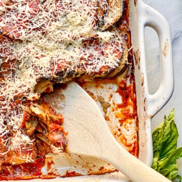 Eggplant Parmesan in a white baking dish with basil as garnish.