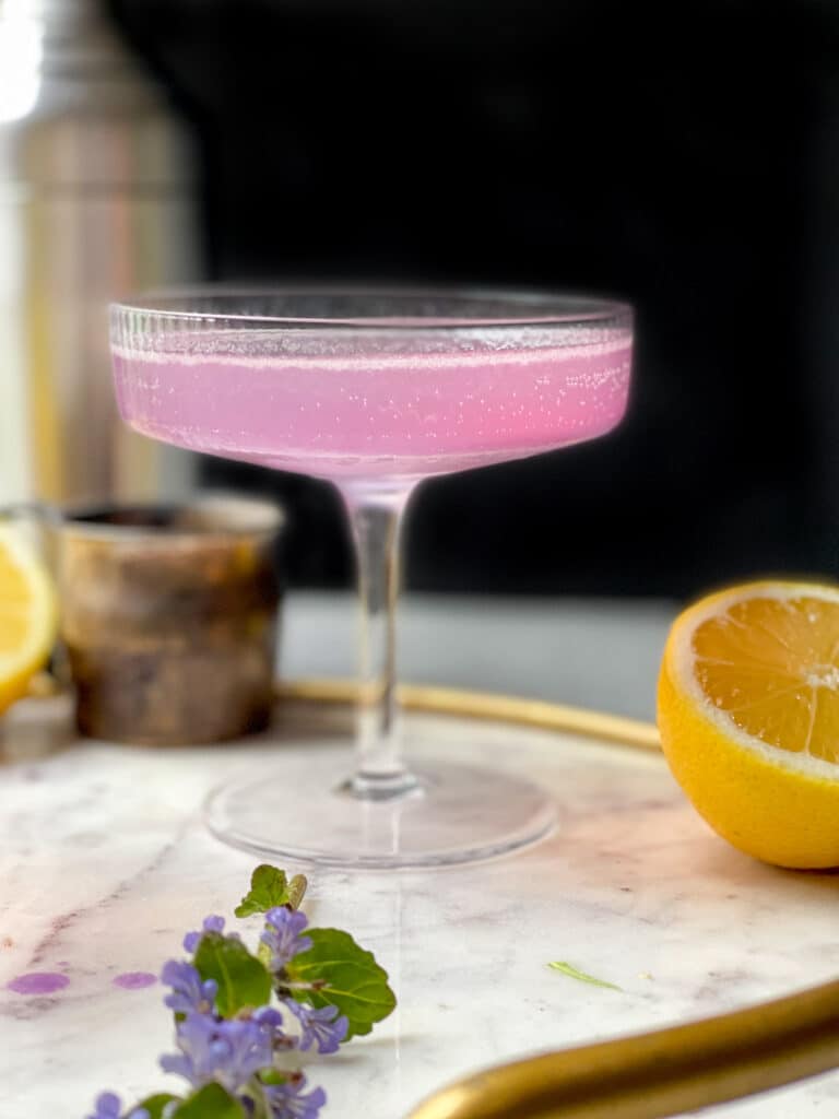 Lavender French 75 Cocktail in glass art deco style glassware on a round white marble tray with a gold rim - The Kitcheneer