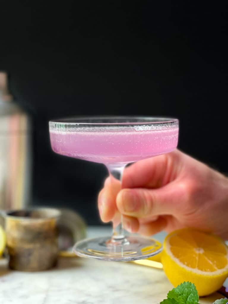 Lavender French 75 Cocktail in a glass art deco style glassware on a round white marble tray with a gold rim - The Kitcheneer 